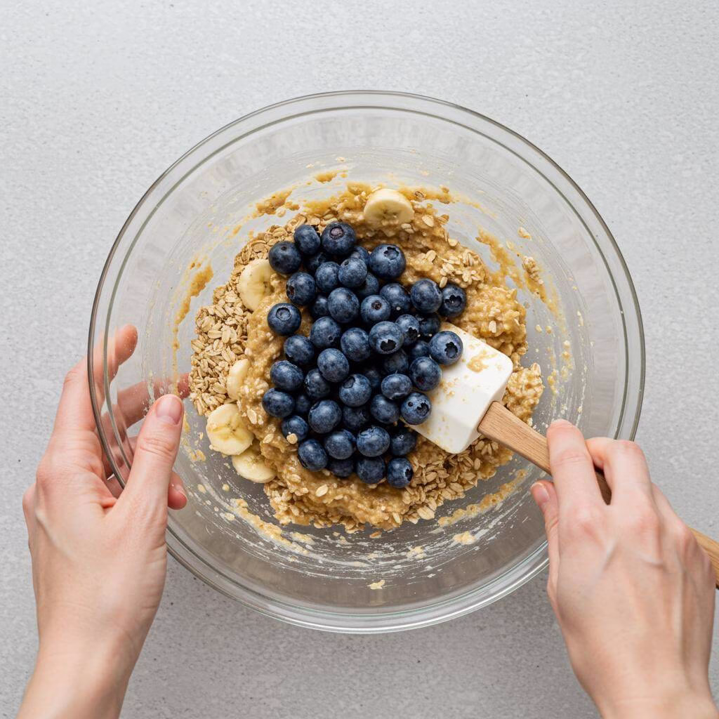 Folding blueberries into batter for blueberry oatmeal cups